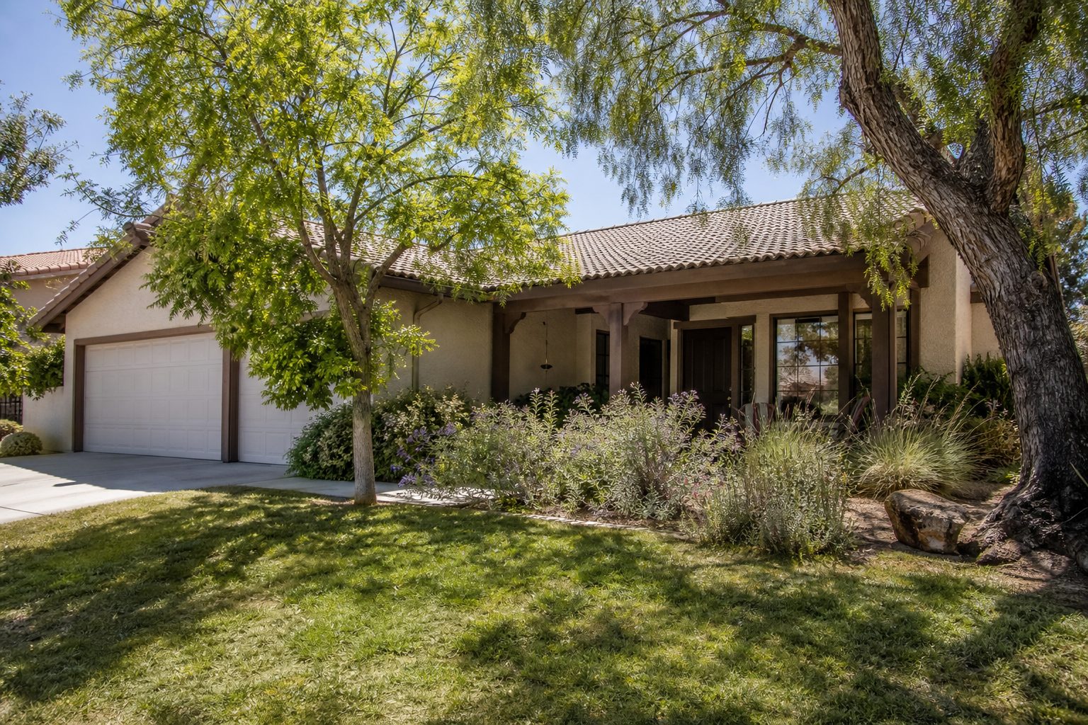 Single-story ranch home with pepper trees and native plantings in south Rancho Cucamonga residential neighborhood, midday sunlight.