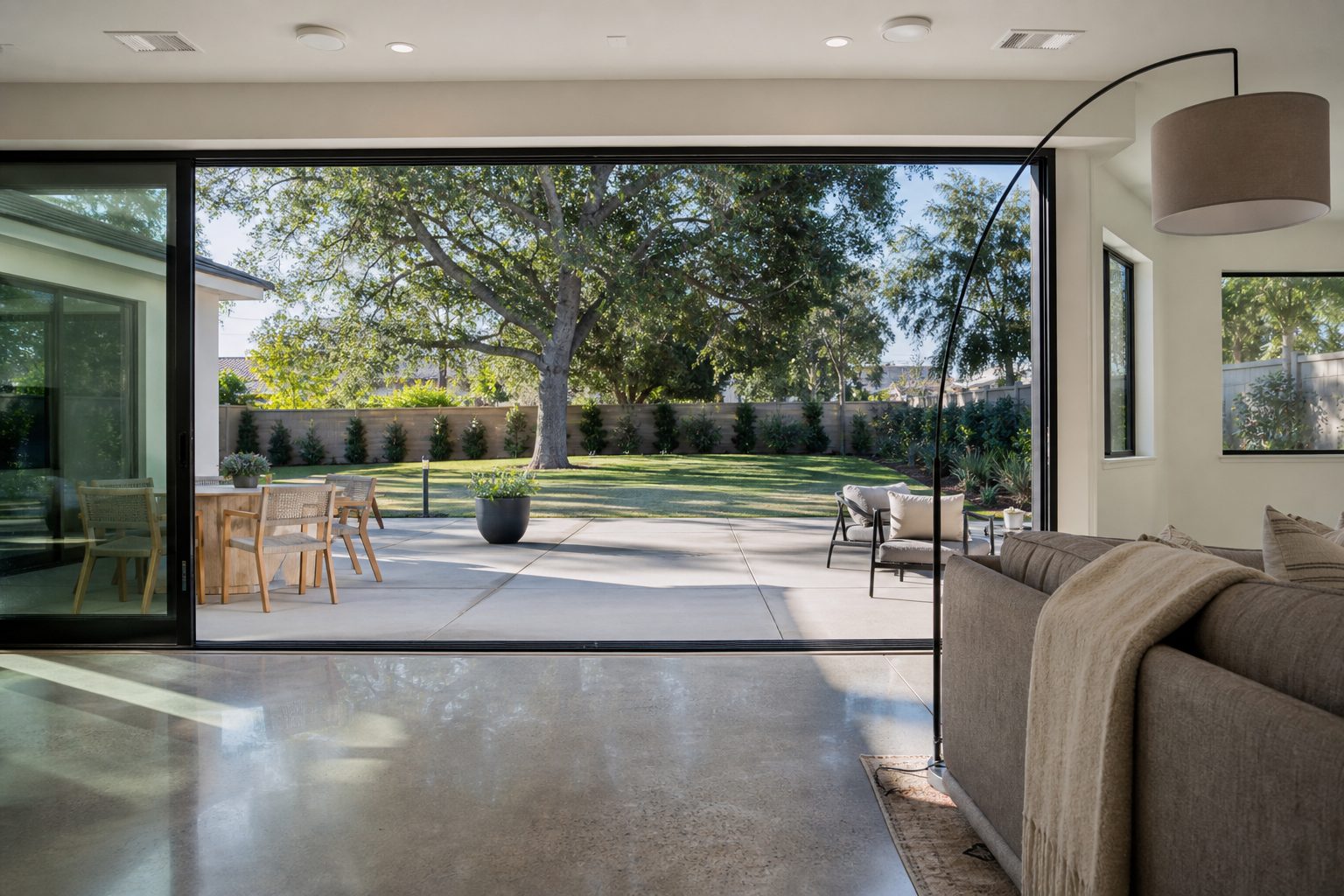 Light-filled interior of single-story home in central Rancho Cucamonga, viewed through open glass doors toward a rear patio and yard with mature