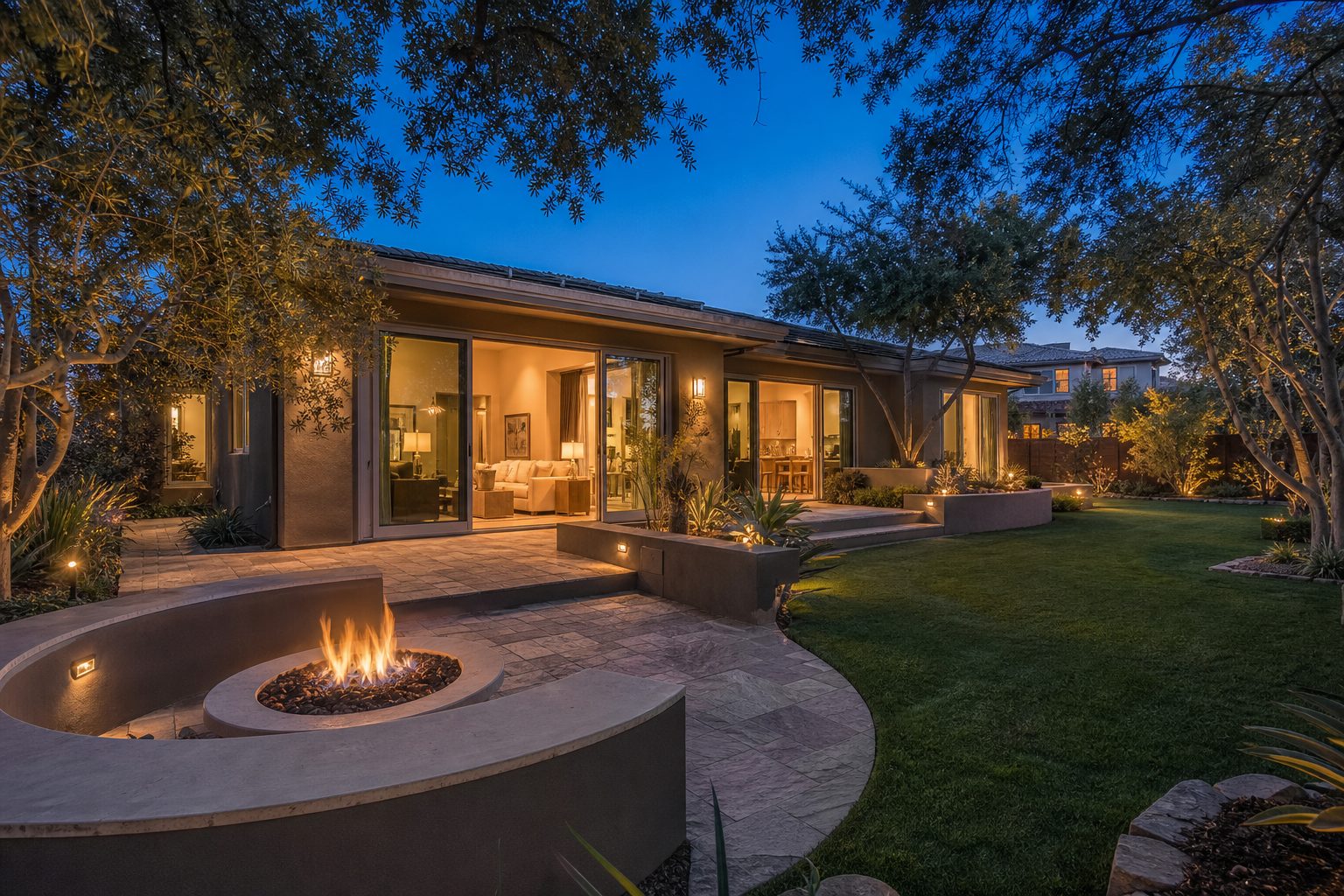Contemporary single-story home with sliding glass doors and illuminated interior during blue hour twilight in Rancho Cucamonga's Victoria Groves