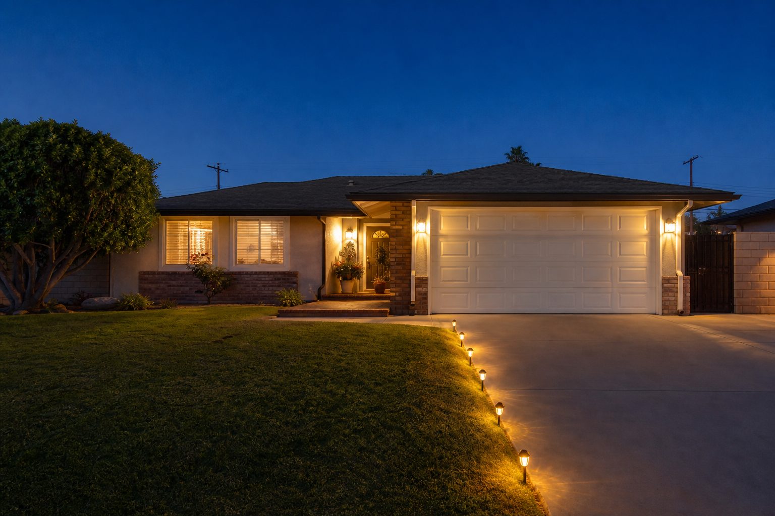 Single-story ranch home with warm interior lights glowing against blue twilight sky in Rancho Cucamonga neighborhood.
