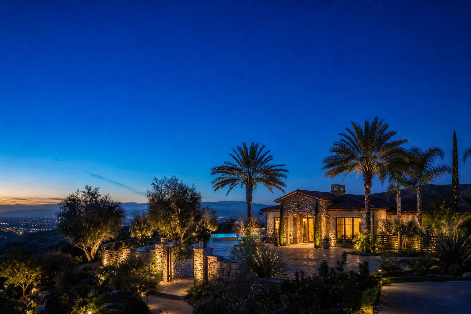Luxury Mediterranean estate in Sheridan Estates at twilight with landscape lighting and valley views, interior lights glowing warm.