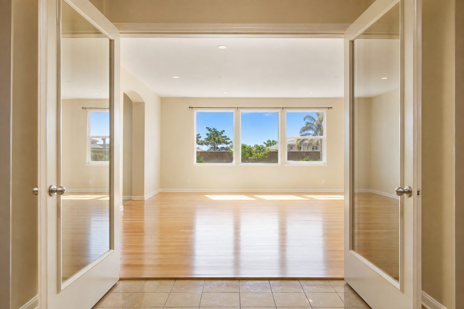 Bright interior living room view through open French doors in Rancho Cucamonga home showing hardwood floors and afternoon sunlight.