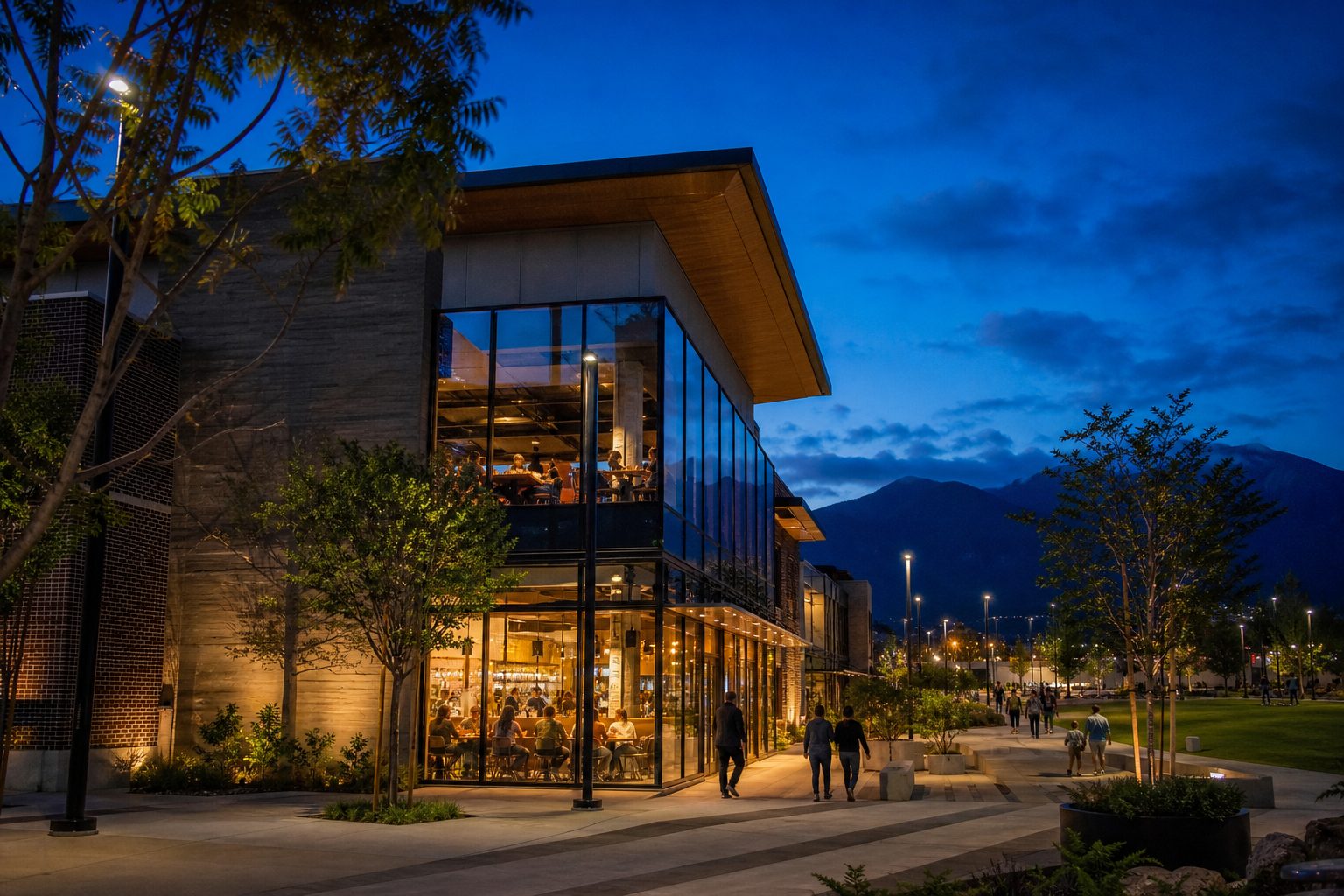 Haven City Market's glass and brick facade at twilight with warm interior glow, outdoor plaza, and landscaping in Rancho Cucamonga's central business